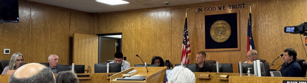 City officials and community members at a government meeting discussing budget.