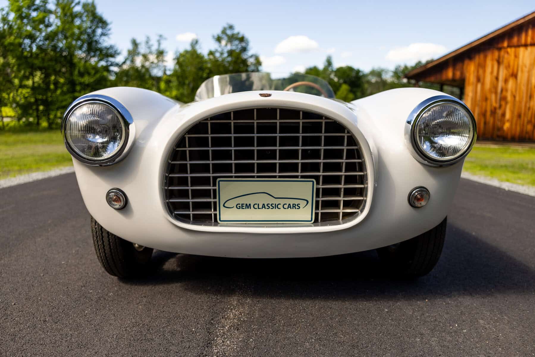 Front view of a vintage white sports car with a black grille and round headlights.