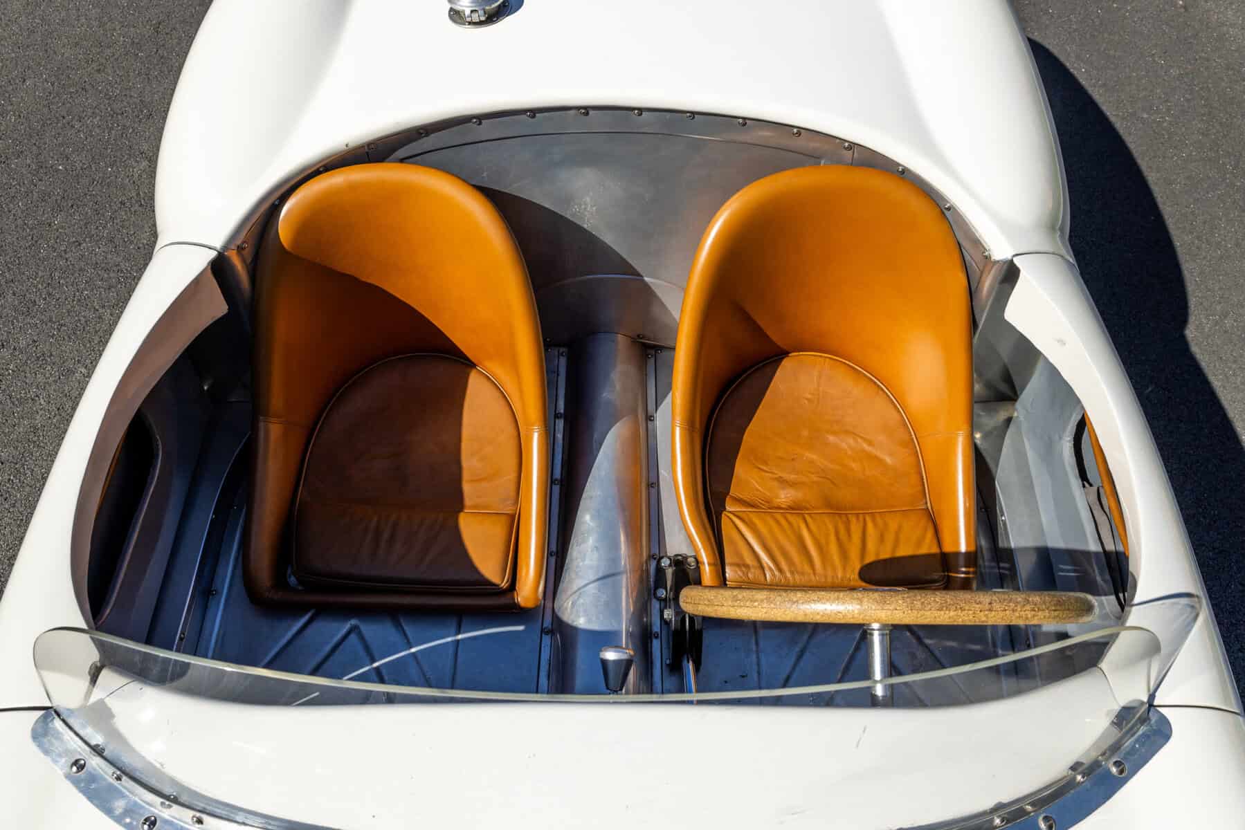 Close-up of vintage car interior with brown leather seats and steering wheel.