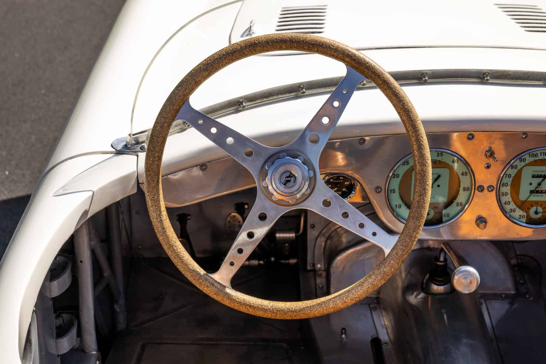 Close-up of vintage car dashboard and steering wheel from above.