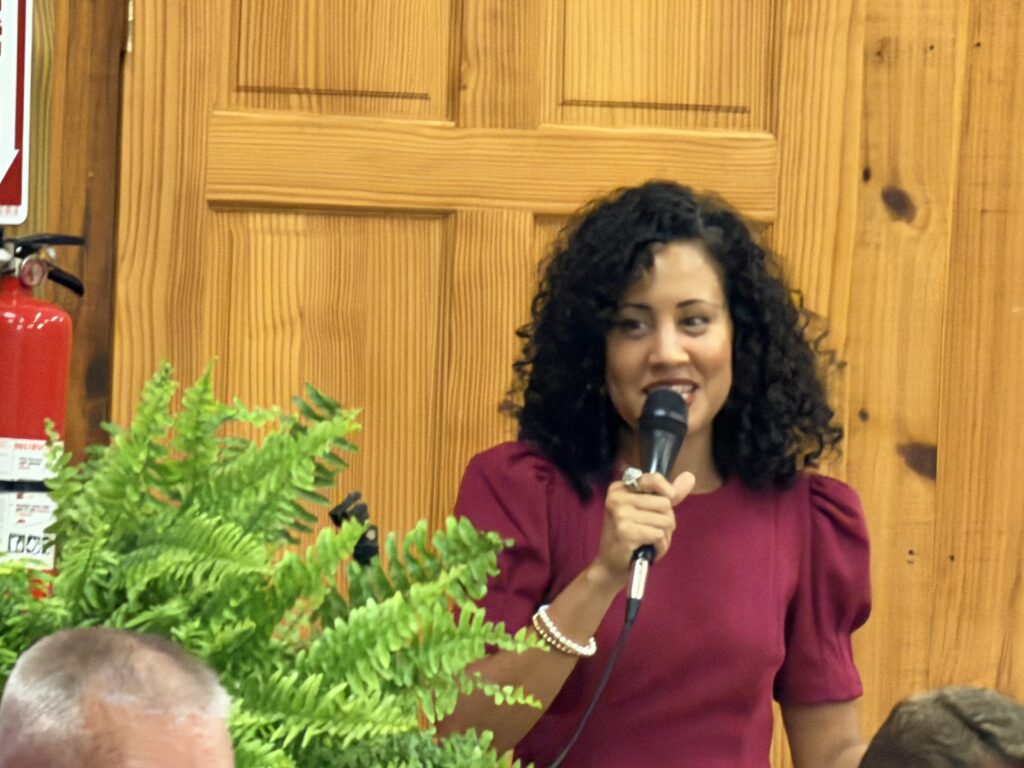 Woman speaking at Macon County GOP campaign event with microphone.