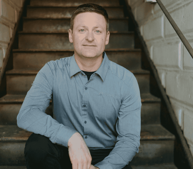 Portrait of a man in a gray shirt sitting on stairs at Macon Sense.