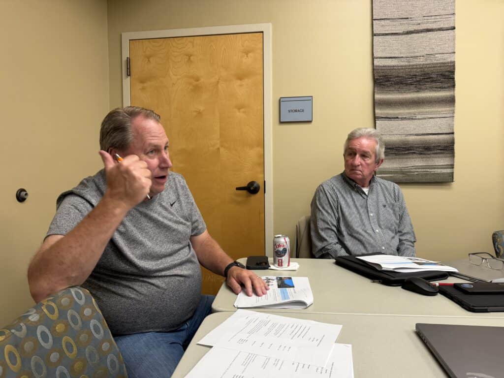 Two men in a meeting room discussing local economic strategies.