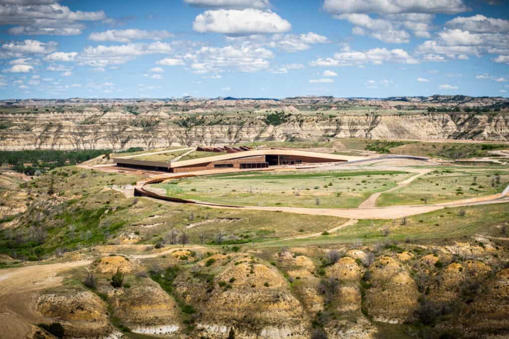 Contemporary building in a canyon landscape with blue sky and clouds.