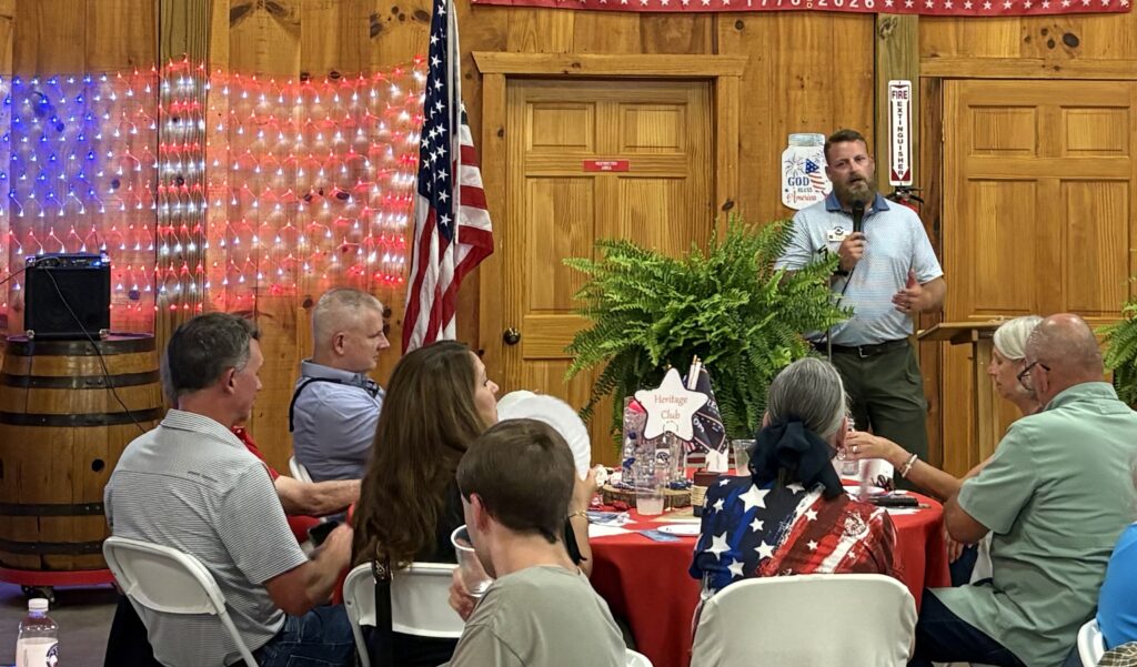 GOP candidate speaking at Macon County campaign event with audience.