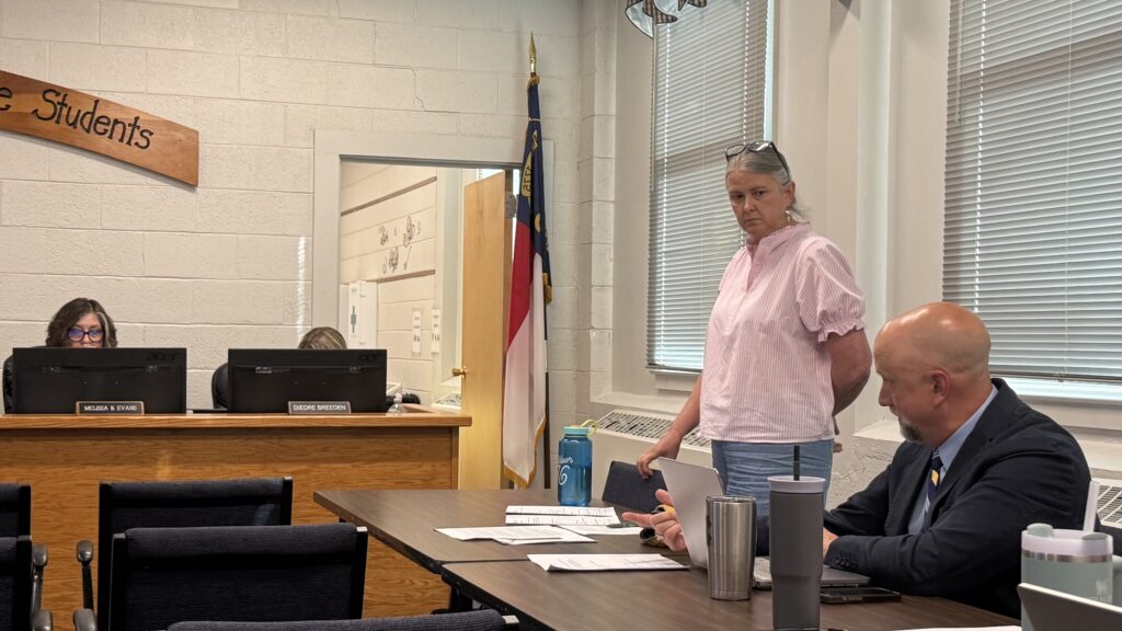 School board members discussing budget and policies in a classroom setting.