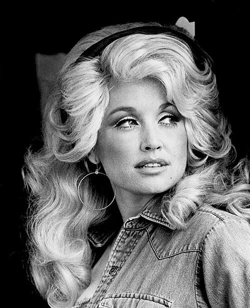 Black and white photo of Dolly Parton with voluminous hair and denim jacket.