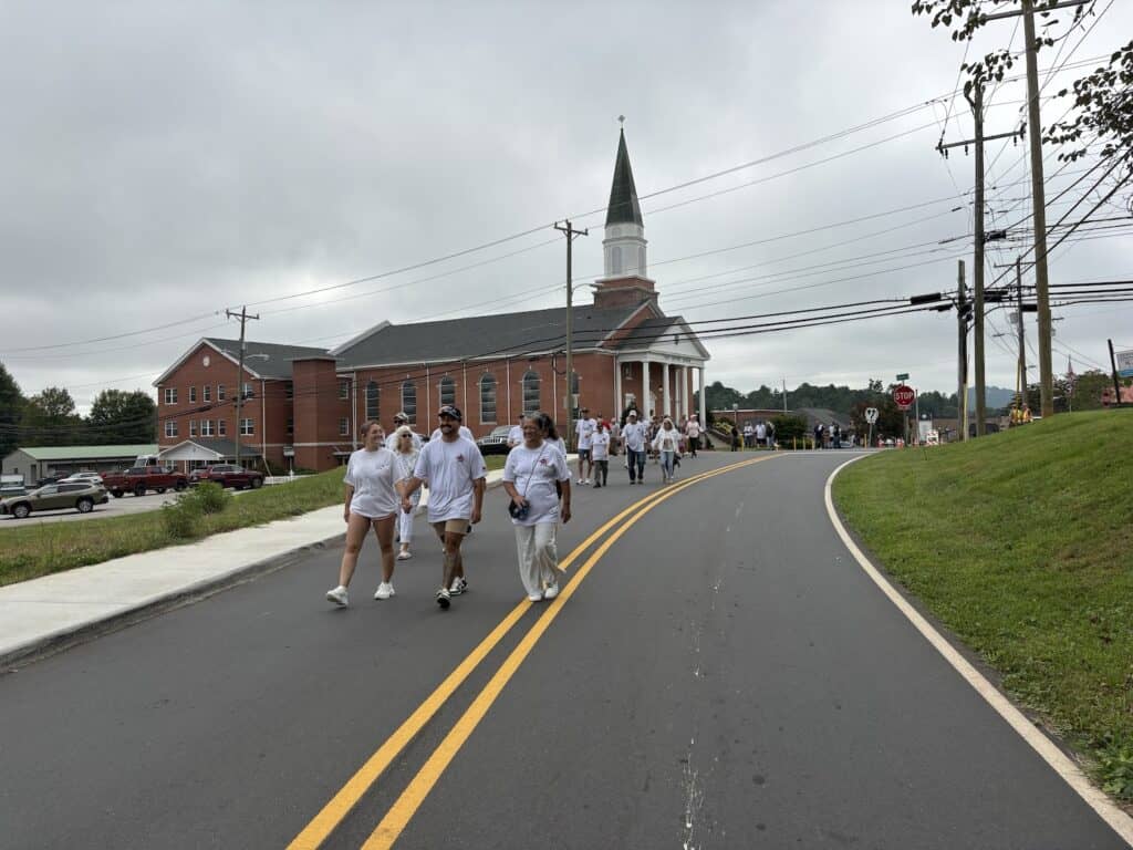 Group of people walking on a road near a church during a community event.