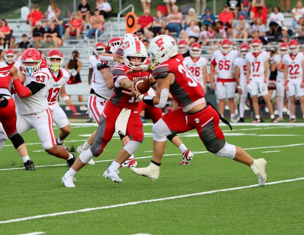 Football players in red and white uniforms during a game on the field.
