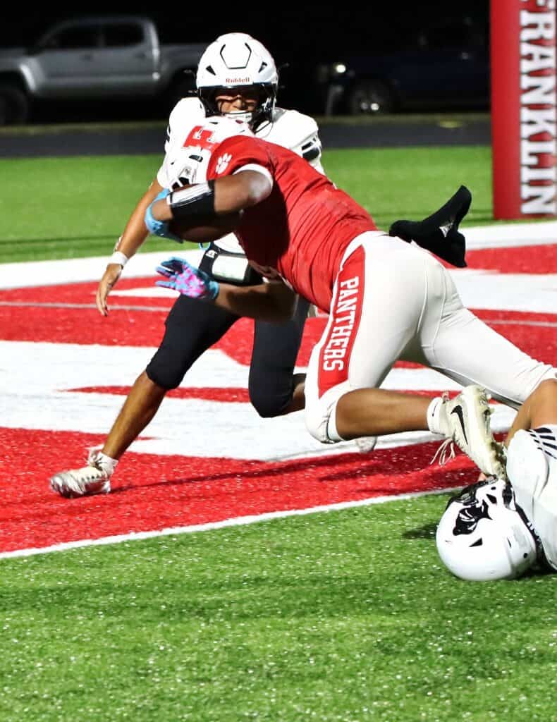 Football player tackled during a game on a brightly lit field.