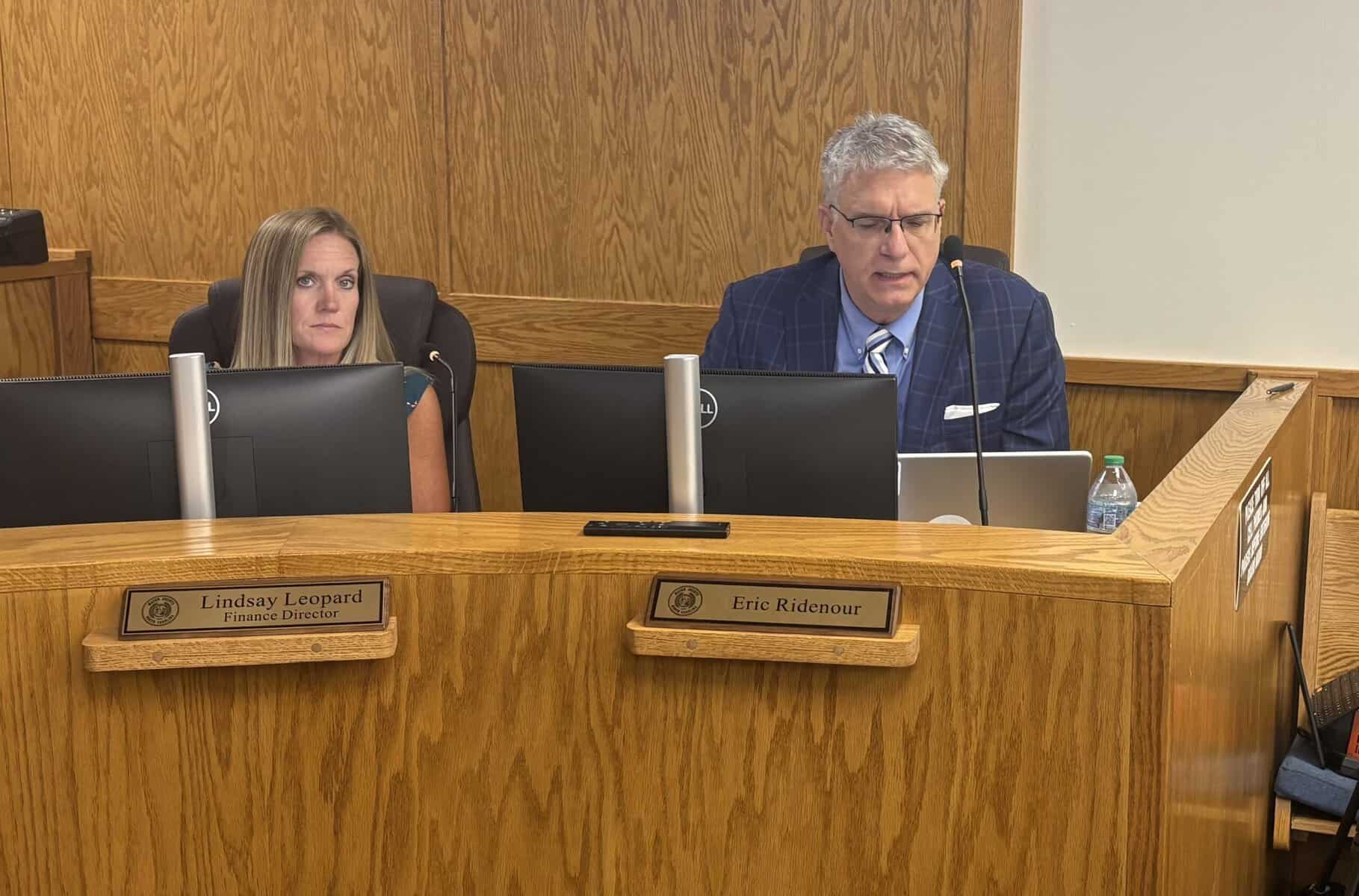 City council meeting with two officials at a wooden desk.