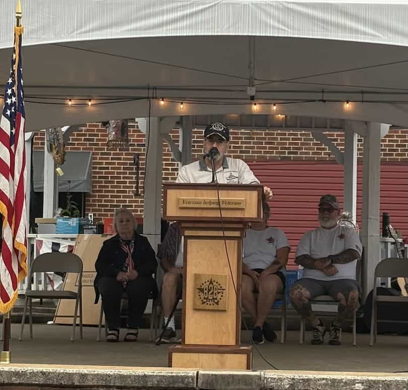 Veterans speaking at a community event under a tent in Macon.