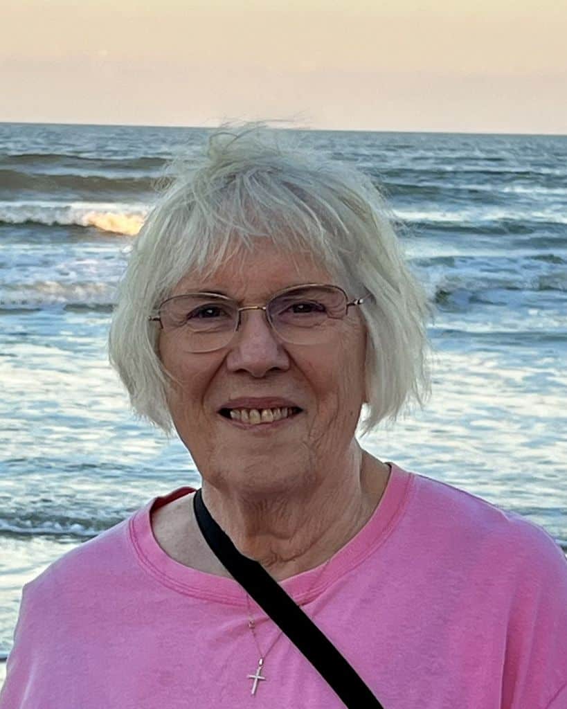 Lillian 'Lil' Gerber smiling at the beach with ocean waves behind her.