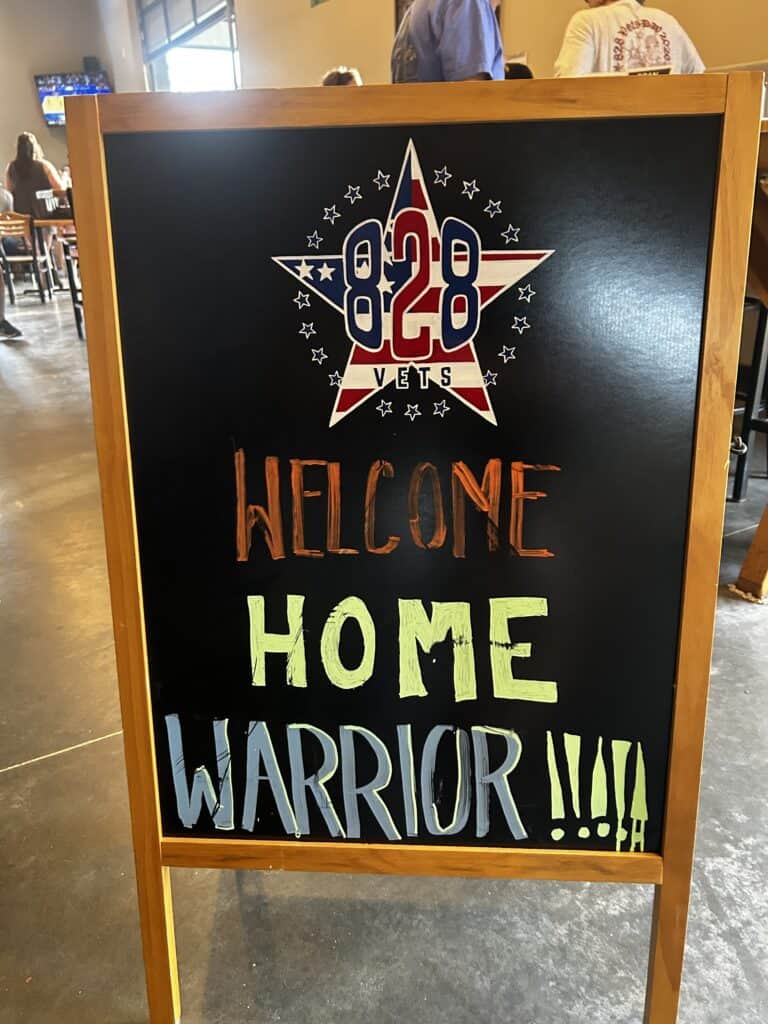 Veterans Day event sign with patriotic design and welcoming message.