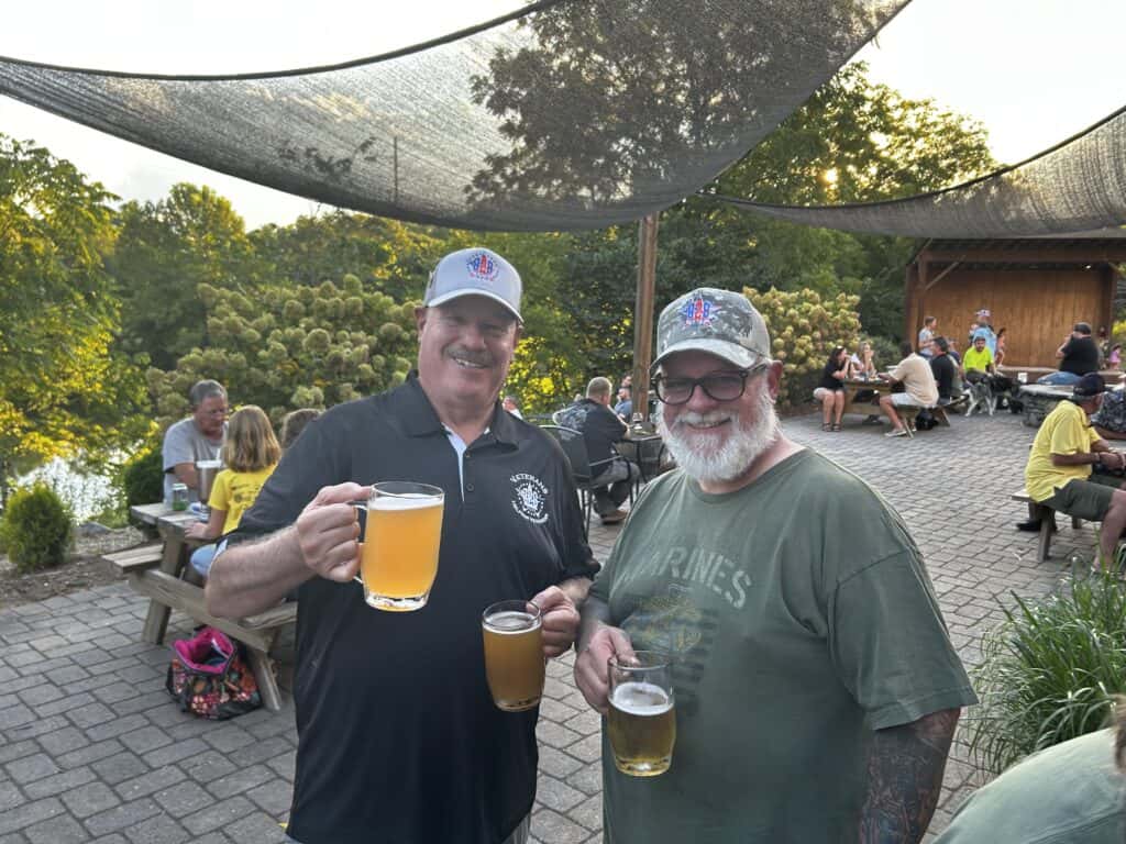 Two veterans enjoying beers outdoors during a celebration event.