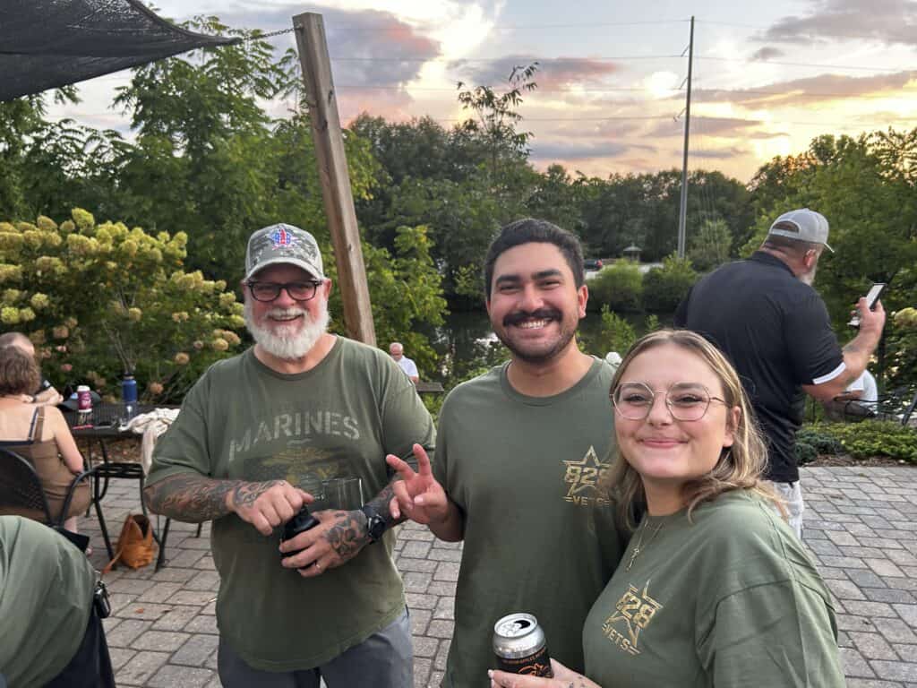 Group of veterans and supporters enjoying outdoor event at sunset.