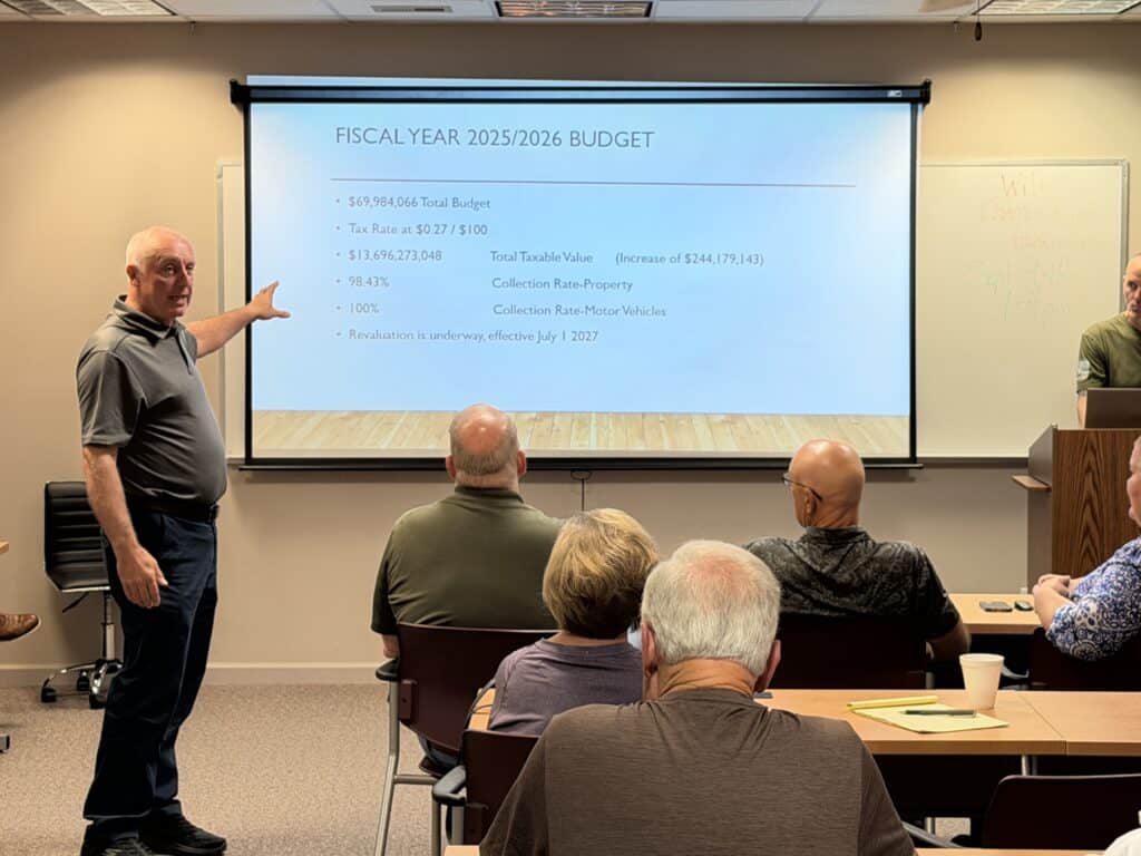 Man presenting fiscal year 2025/2026 budget to a group of professionals.