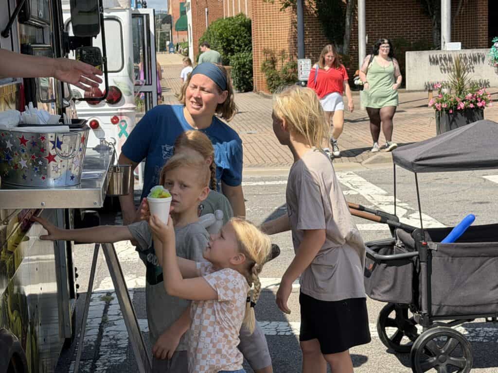 People enjoying ice cream at Macon Sense food truck on a sunny day.