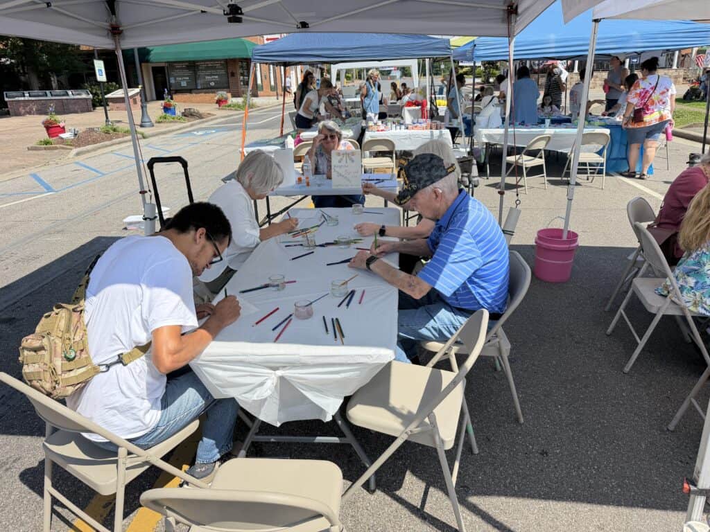 People participating in outdoor art workshop at Macon Sense event.
