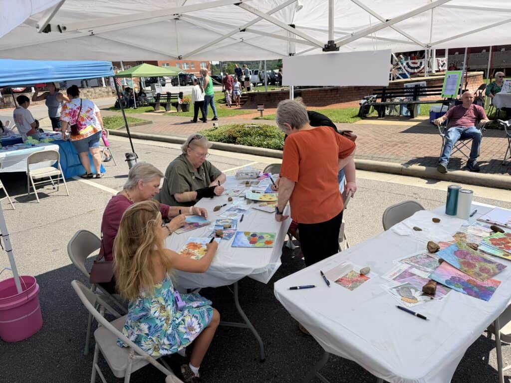 People creating art at outdoor community event in Macon.