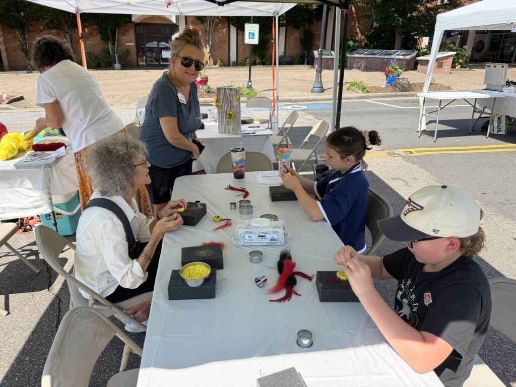 People making crafts at outdoor community event in Macon.
