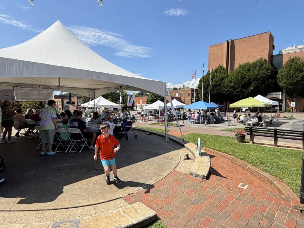 People enjoying outdoor community event at Macon Square with tents and activities.