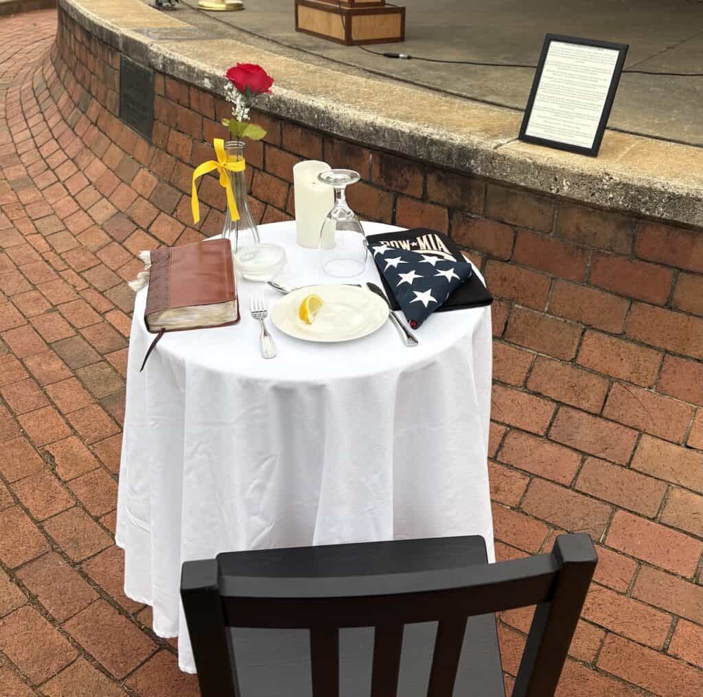Memorial table with flowers, flag, and framed tribute for Veterans Day.