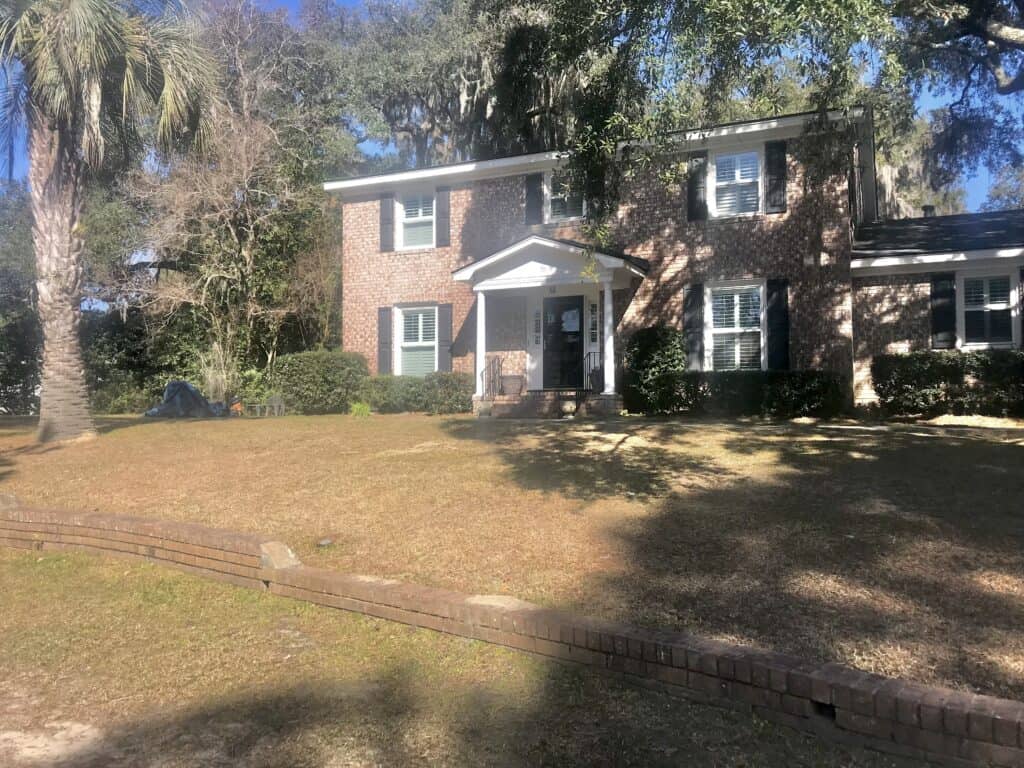Beautiful brick house with lush garden and mature trees in North Carolina.