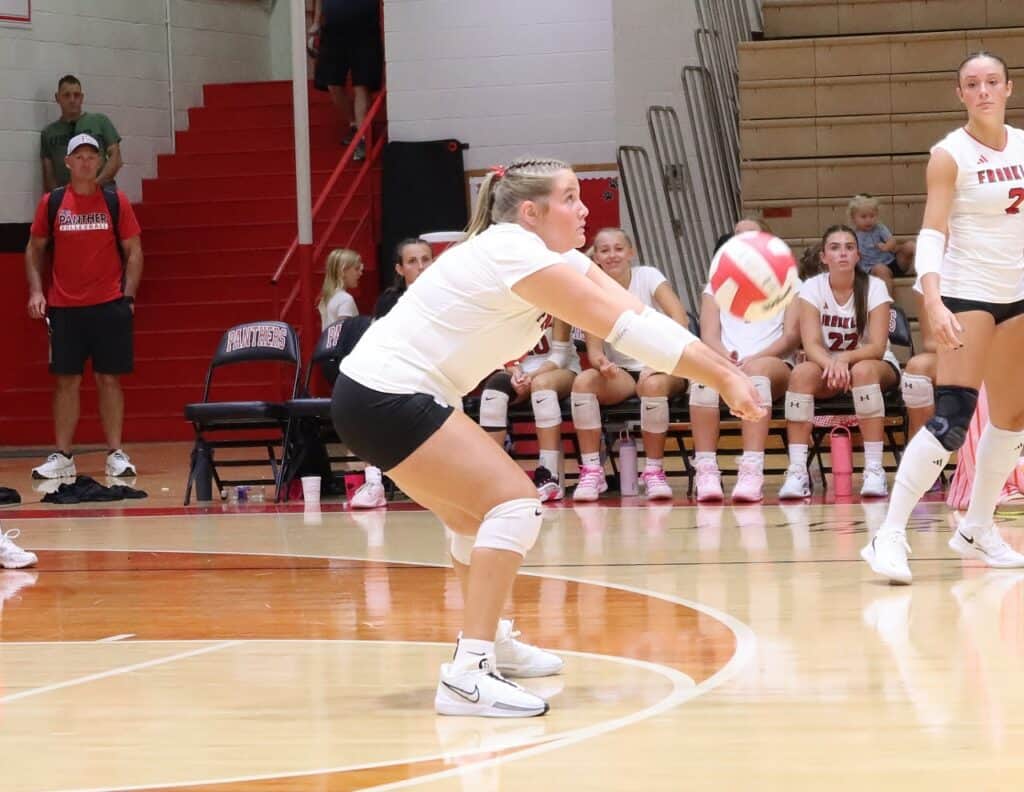 Female volleyball player diving to save the ball during a match.
