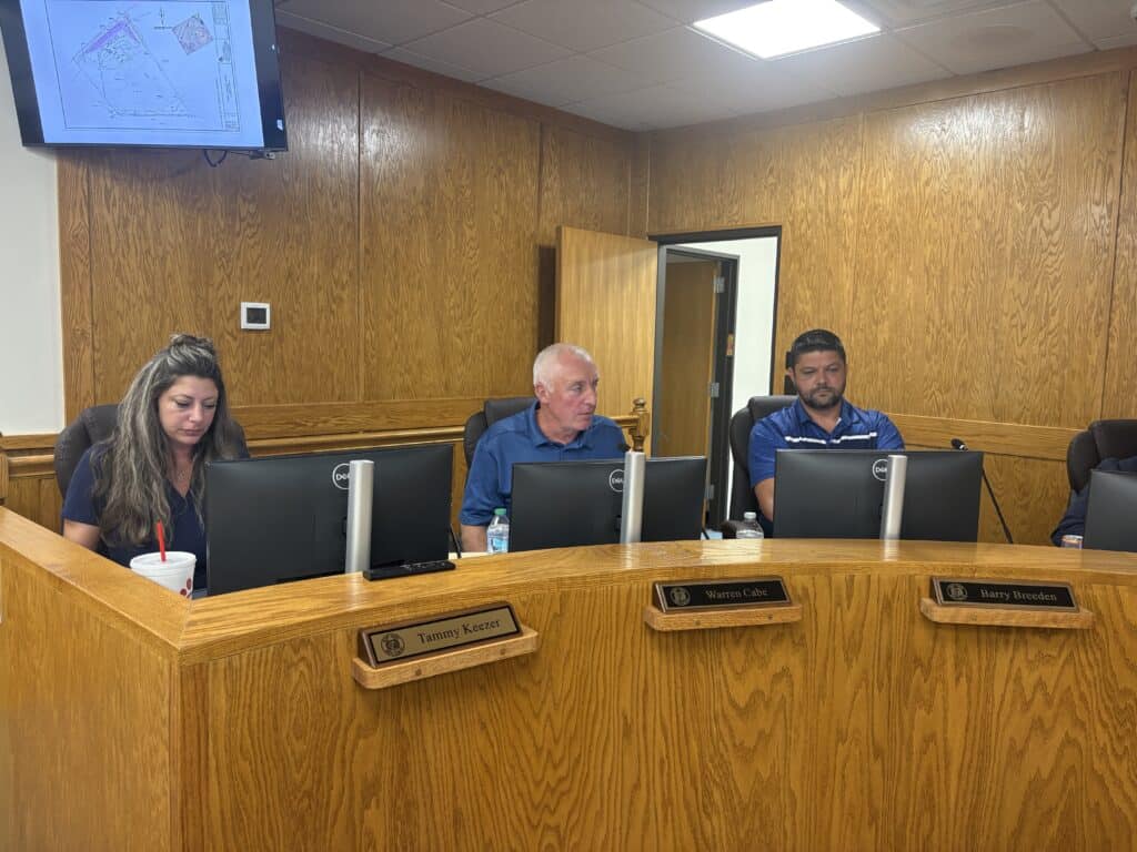 City council members seated at a wooden desk during a meeting.