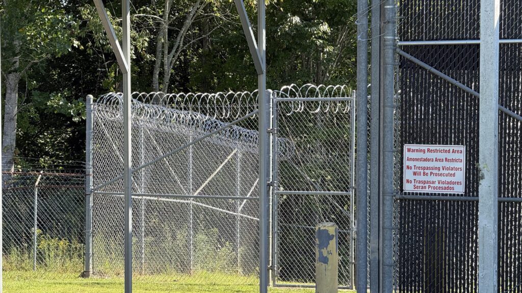 Fenced area with barbed wire and warning signs for restricted access.
