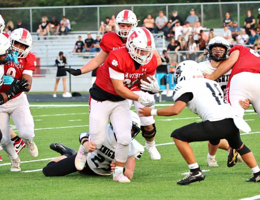 Young football players in red and white uniforms during a game.