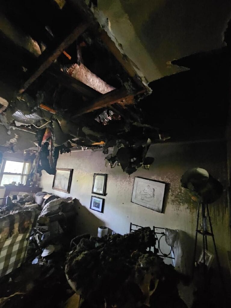 Interior of apartment with extensive fire damage and charred ceiling.