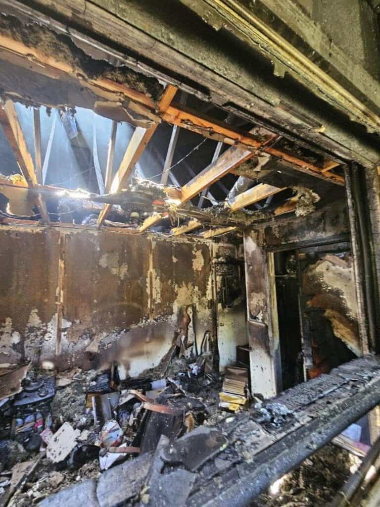 Interior of Harrison Garden Apartments after fire damage, showing burnt walls and ceiling.