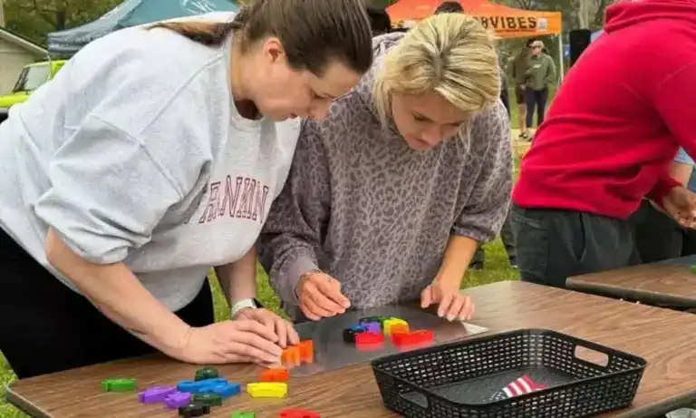 Two women playing a game with colorful pieces at an outdoor event.