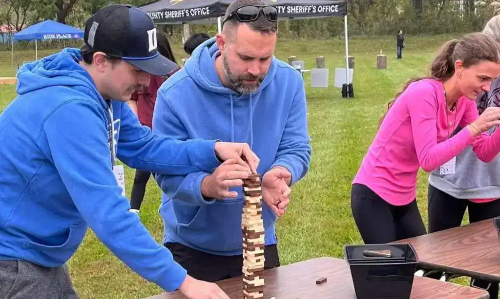 Group of people playing Jenga game outdoors during Treasure Quest event.