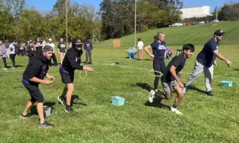 Group of people participating in a tug-of-war game outdoors on a grassy field.