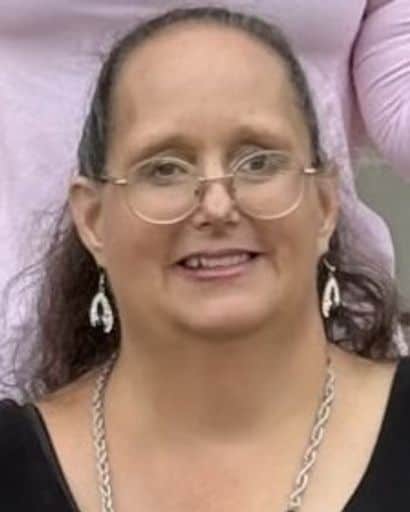 Portrait of a woman with glasses and earrings, smiling at the camera.