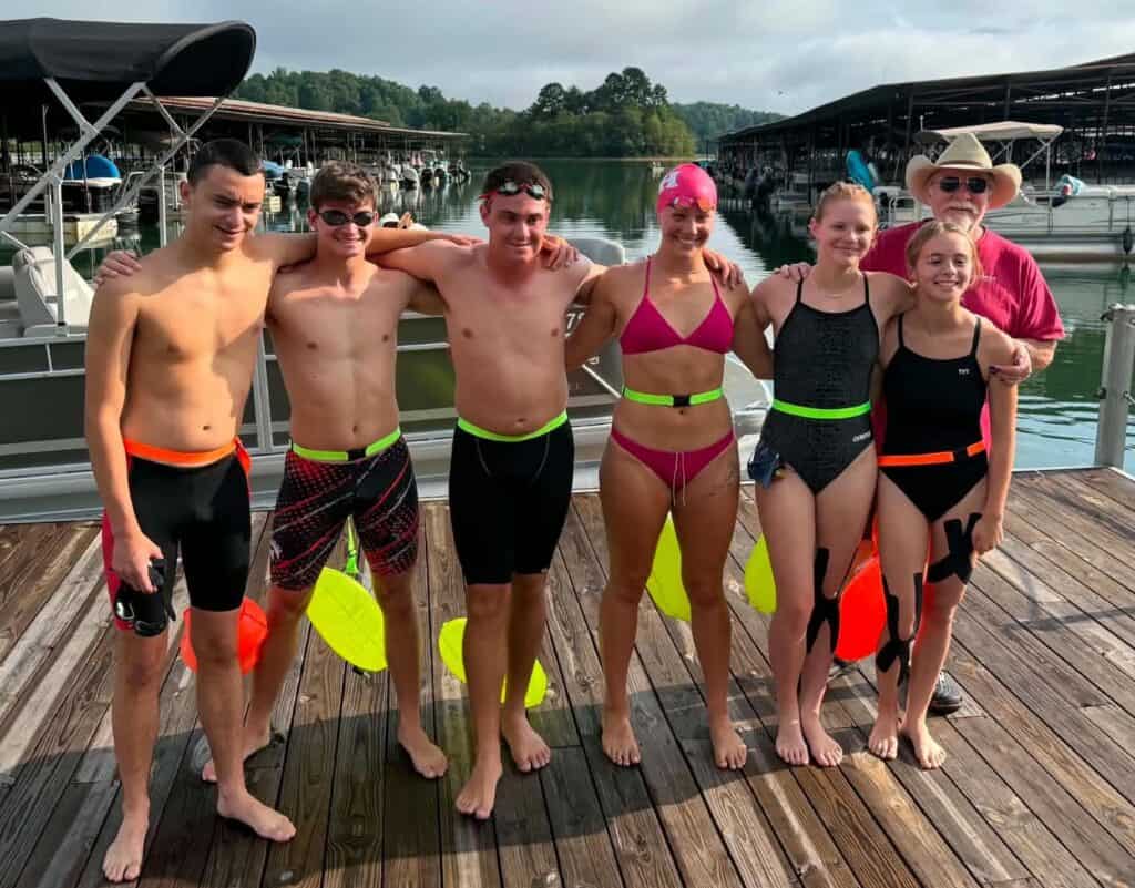 Group of young swimmers in swim gear at lake dock for AAU Junior Olympics.