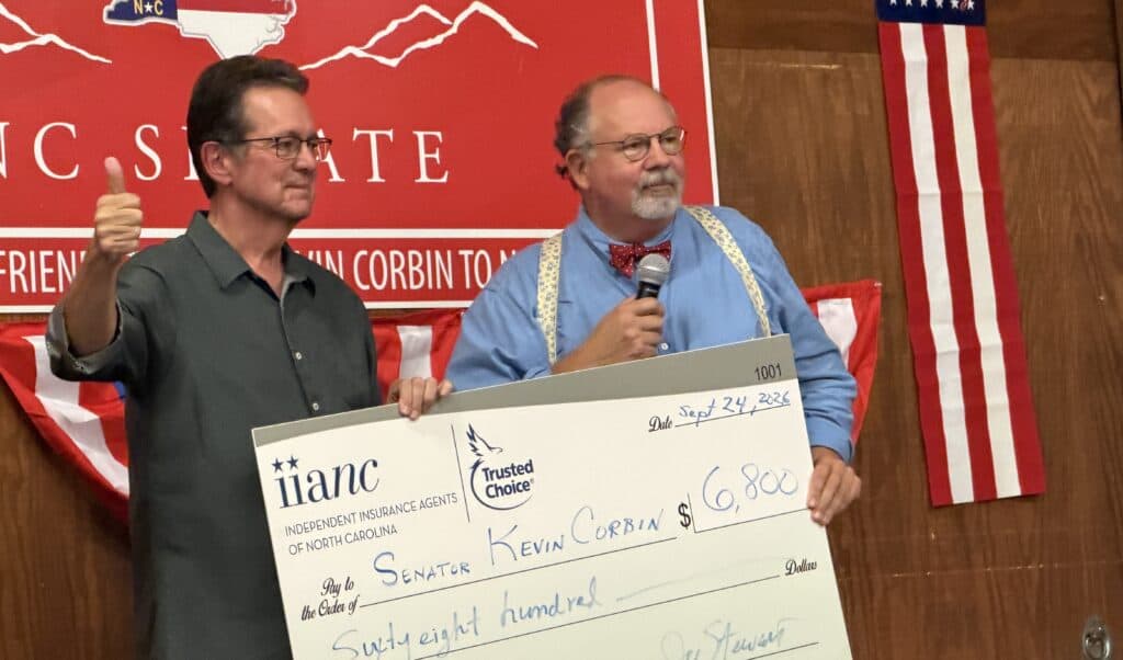 Corbin and supporter holding a large check at campaign event.