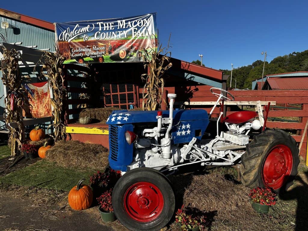 Vintage blue tractor at Macon County Fair with pumpkins and fall decorations.