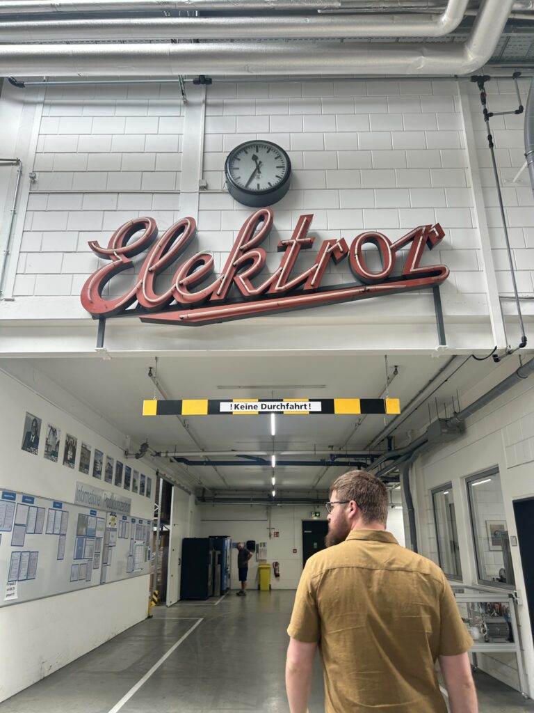 Elektrizitätswerk Elektroz sign in industrial setting with clock overhead.