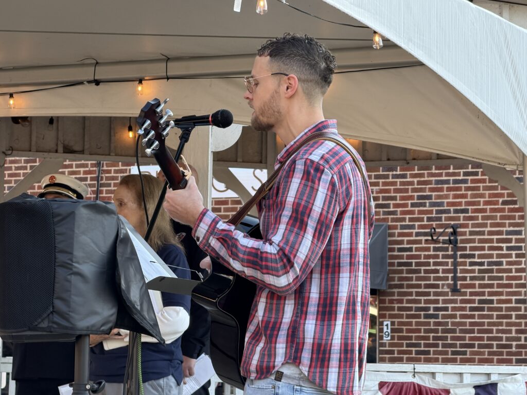 Musician playing guitar and singing at Macon Sense event.