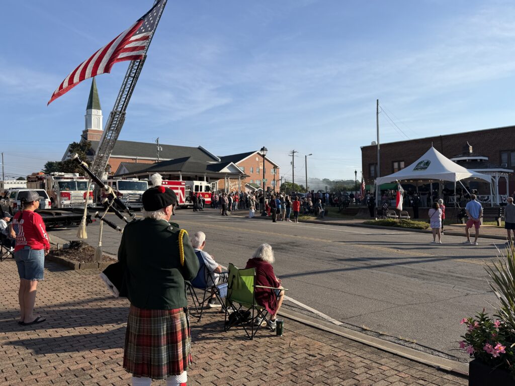 People gather at Macon 9/11 memorial with American flag and fire trucks.