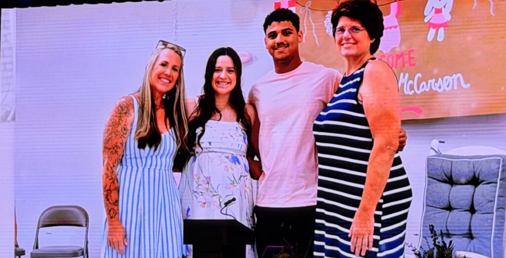 Group of four diverse people smiling at an event with a colorful background.