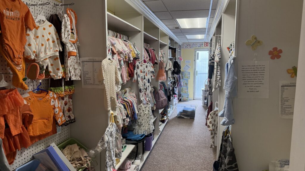 Children's clothing aisle at Pregnancy Care Center with colorful outfits on display.