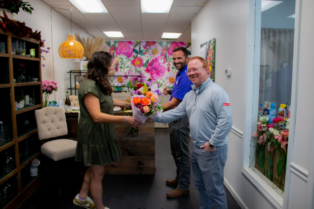 Group of people celebrating with flowers in Highlands office.