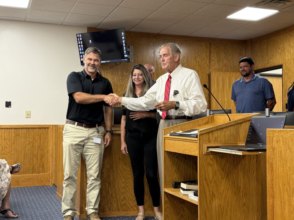 Officials shake hands during a meeting on budget planning and services.