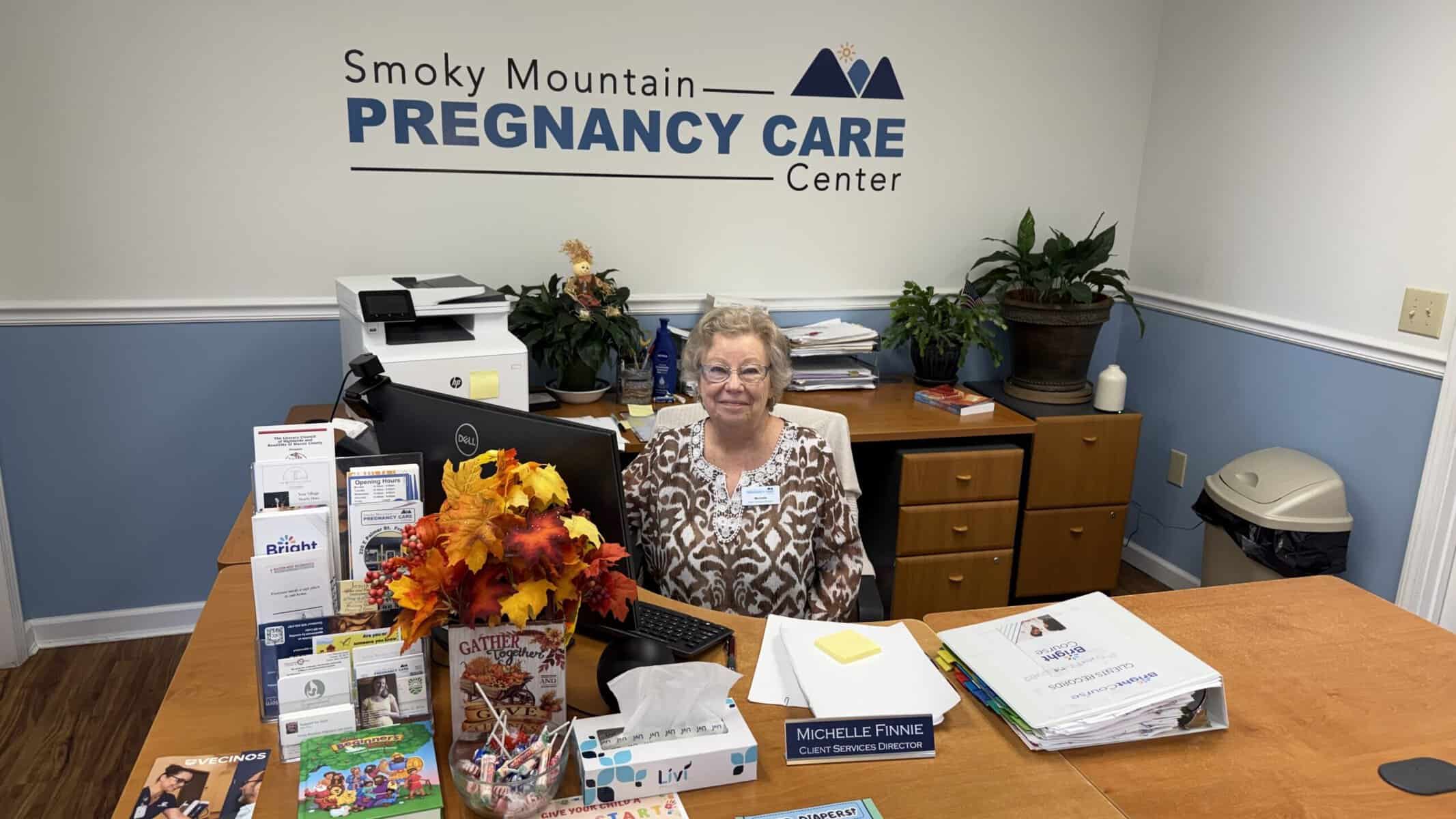 Smoky Mountain Pregnancy Care Center receptionist smiling at desk.