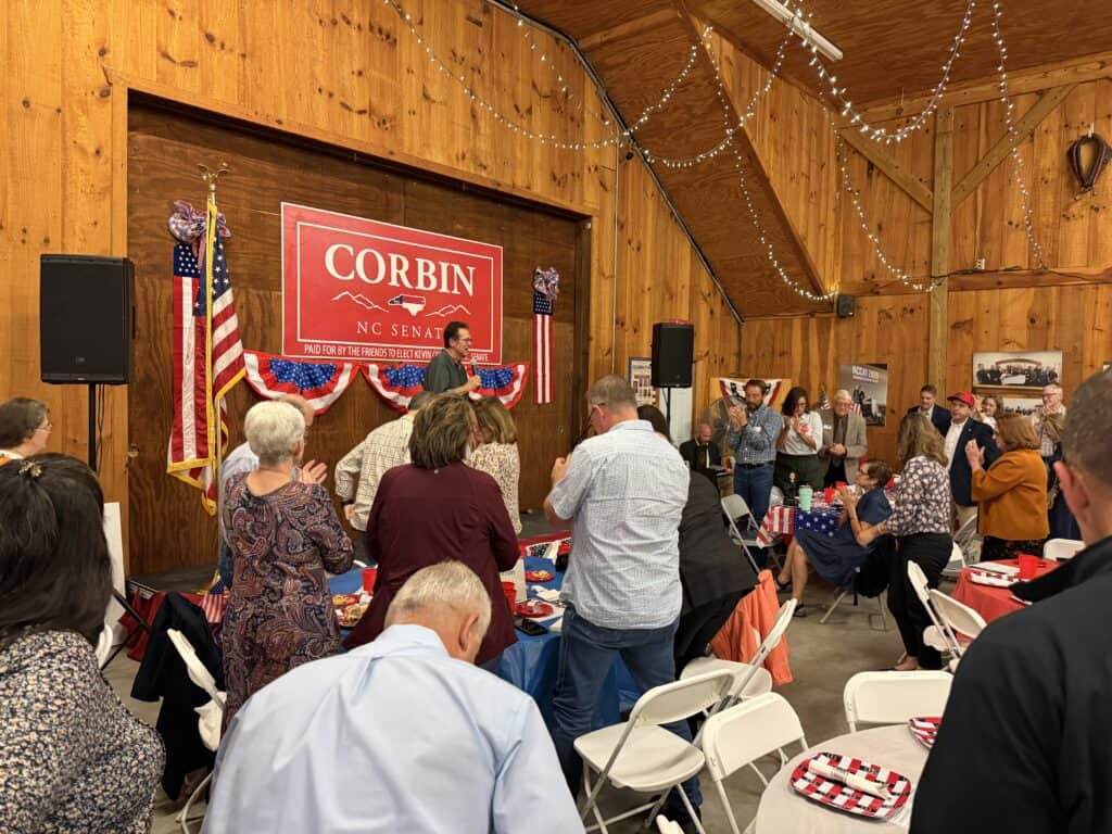 People attending Corbin's re-election campaign event in a rustic hall.